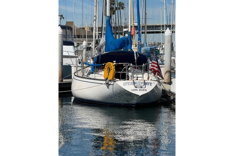 1985 Catalina 38 sailboat docked in marina, displaying American flag and "Stardust" name.