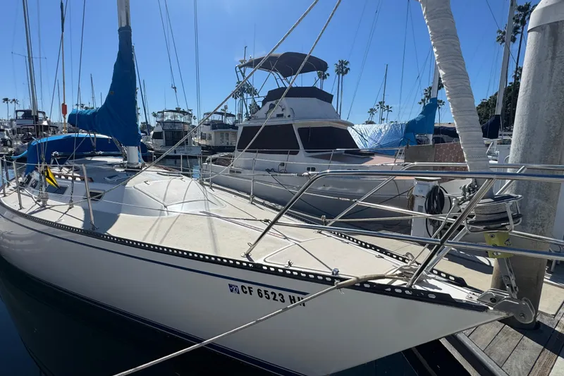 1985 Catalina 38 sailboat docked in marina, surrounded by other boats.