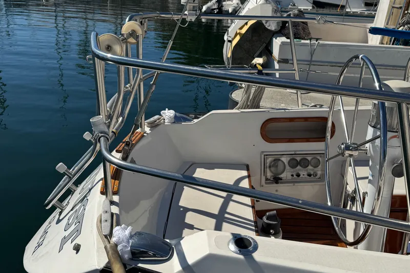 1985 Catalina 38 sailboat cockpit with steering wheel and control panel, docked at marina.