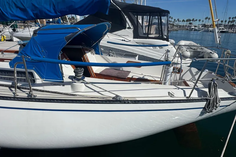 1985 Catalina 38 sailboat docked in marina, featuring blue canopy and sleek design.