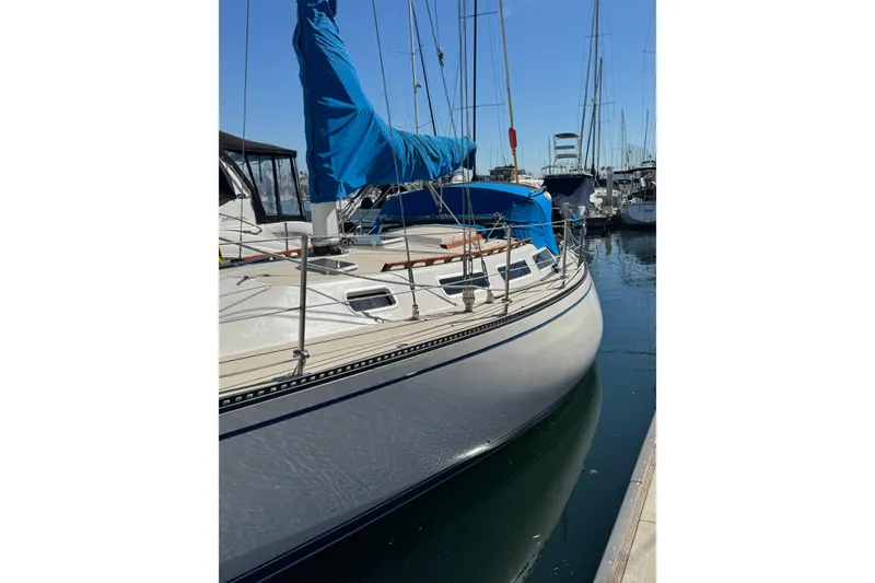 1985 Catalina 38 sailboat docked in a marina, featuring blue sail cover.