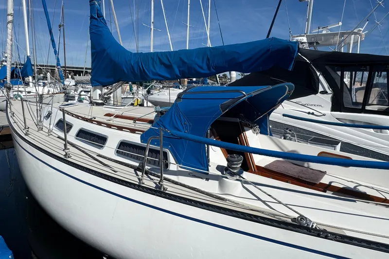 1985 Catalina 38 sailboat docked in marina, featuring blue sail cover.