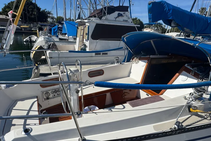 1985 Catalina 38 sailboat docked in marina, featuring spacious cockpit and blue canopy.