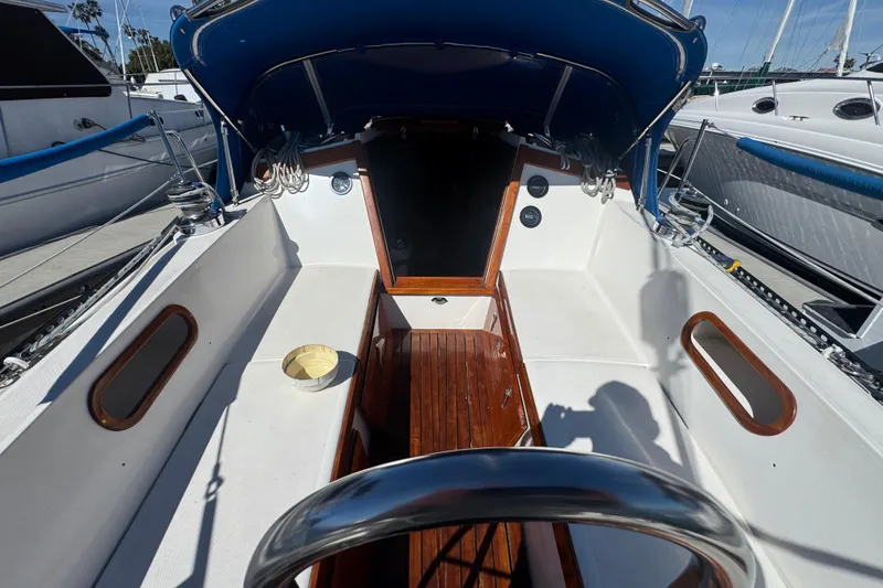 Cockpit of a 1985 Catalina 38 sailboat with wooden accents and blue canopy.