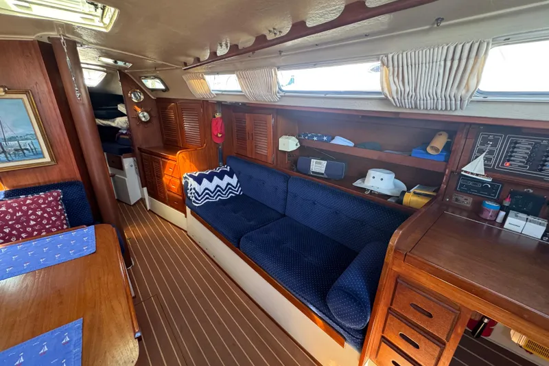 Interior of a 1985 Catalina 38 sailboat with cozy seating and wooden cabinetry.