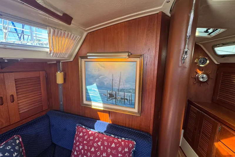 Interior of 1985 Catalina 38 sailboat with nautical painting and cozy seating area.