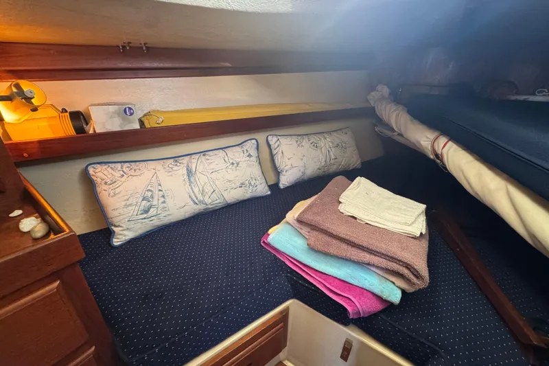 Cozy cabin interior of 1985 Catalina 38 sailboat with nautical-themed pillows and folded towels.