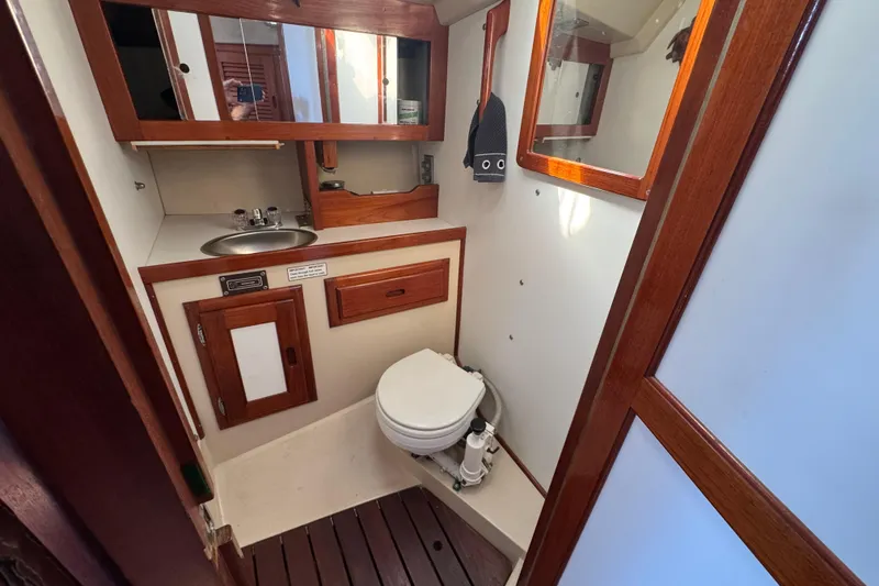 1985 Catalina 38 yacht bathroom with wooden cabinetry, sink, and toilet.
