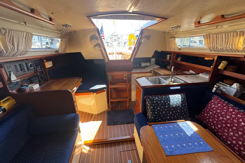 Interior of a 1985 Catalina 38 sailboat with cozy seating and wooden finishes.