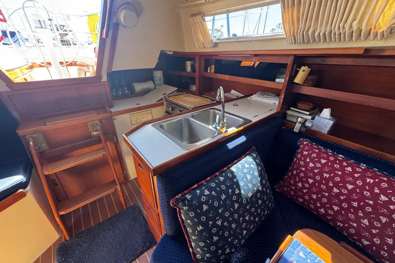 Interior of a 1985 Catalina 38 sailboat with cozy seating and compact kitchen area.