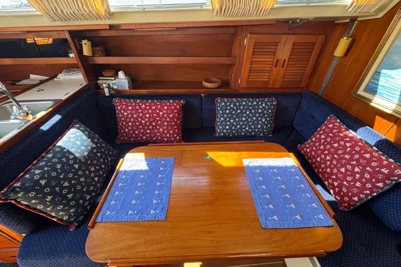 Cozy interior of a 1985 Catalina 38 sailboat with cushioned seating and wooden table.