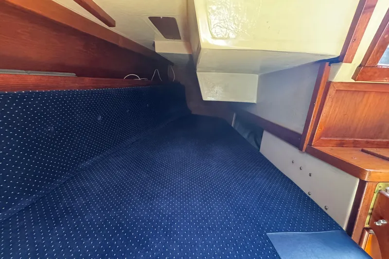 Interior cabin of 1985 Catalina 38 sailboat with blue upholstery and wooden accents.