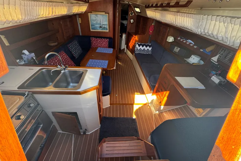 Interior of 1985 Catalina 38 sailboat with kitchen, seating, and wooden flooring.