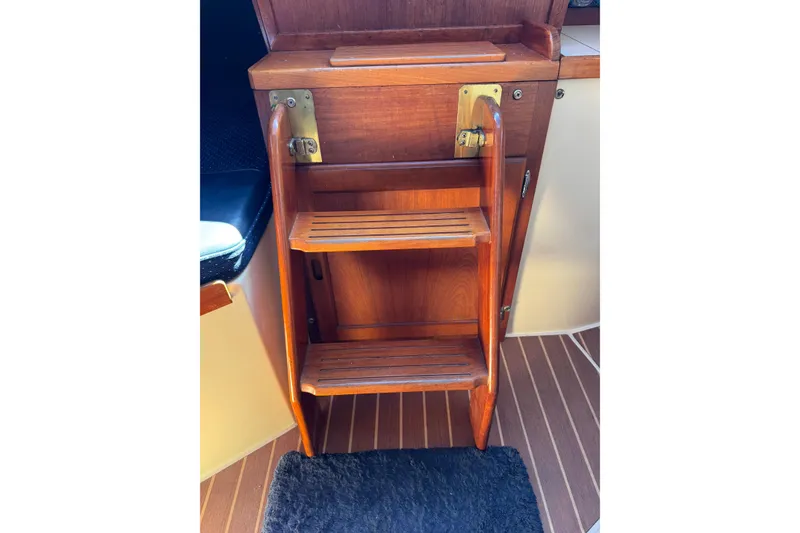 Wooden steps inside a 1985 Catalina 38 sailboat, featuring brass hinges and nautical design.