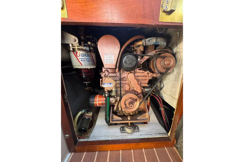 Engine compartment of a 1985 Catalina 38 sailboat, featuring diesel components and filters.