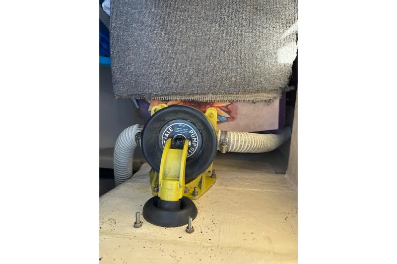1985 Catalina 38 boat bilge pump with hoses and carpeted cover.