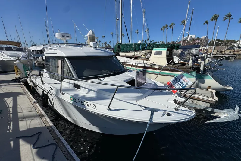 2020 Jeanneau NC 795 boat docked, for sale sign visible, clear blue sky background.