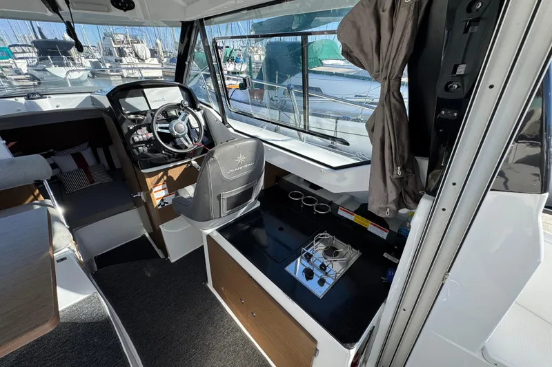 Interior of 2020 Jeanneau NC 795 boat with steering wheel and compact kitchen area.