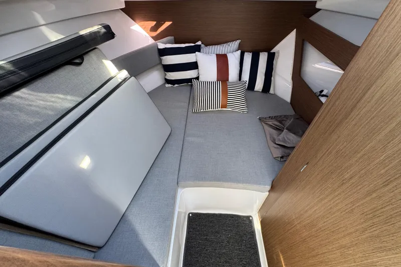 Cozy cabin interior of 2020 Jeanneau NC 795 with striped cushions and wooden accents.