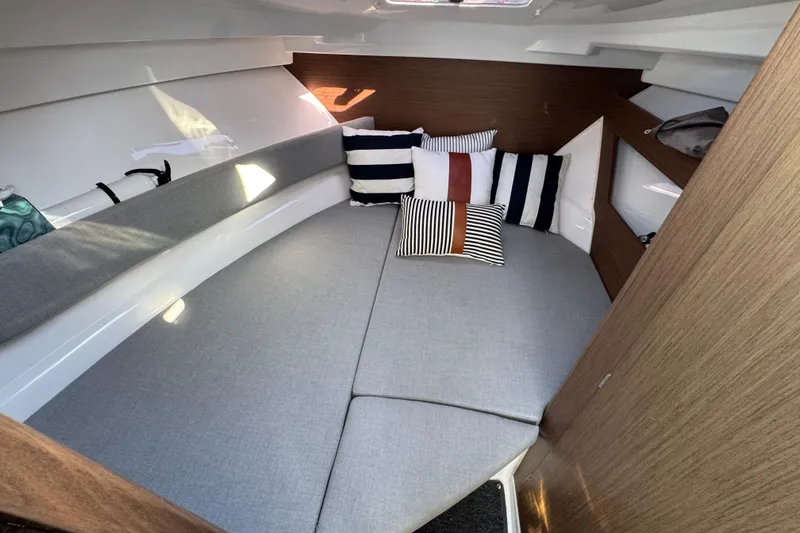 Cozy interior cabin of 2020 Jeanneau NC 795 with striped cushions and wood accents.