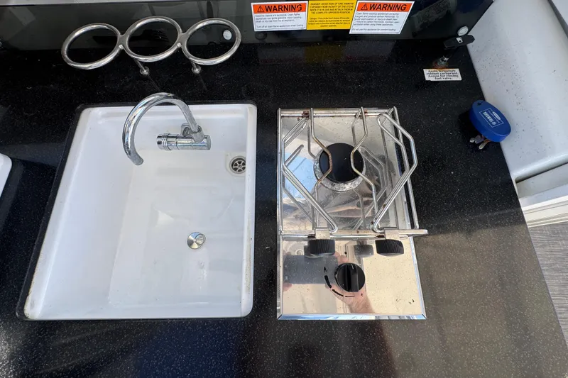 Compact kitchen area on 2020 Jeanneau NC 795 boat with sink and stove.