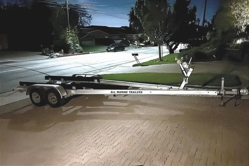 Trailer for Jeanneau NC 795 boat, parked on a residential street at night.