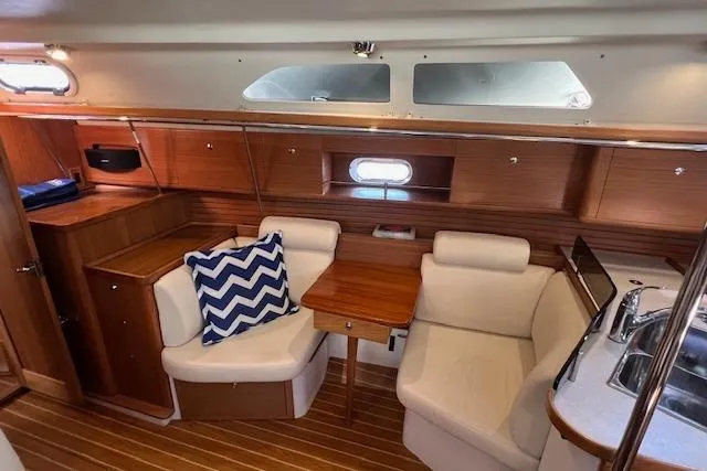 Interior of 2016 Catalina 385 sailboat with cozy seating and wooden finishes.