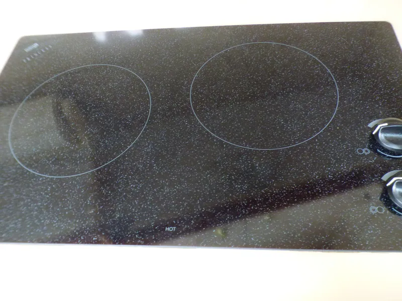 Glass ceramic cooktop with two burners and control knobs.