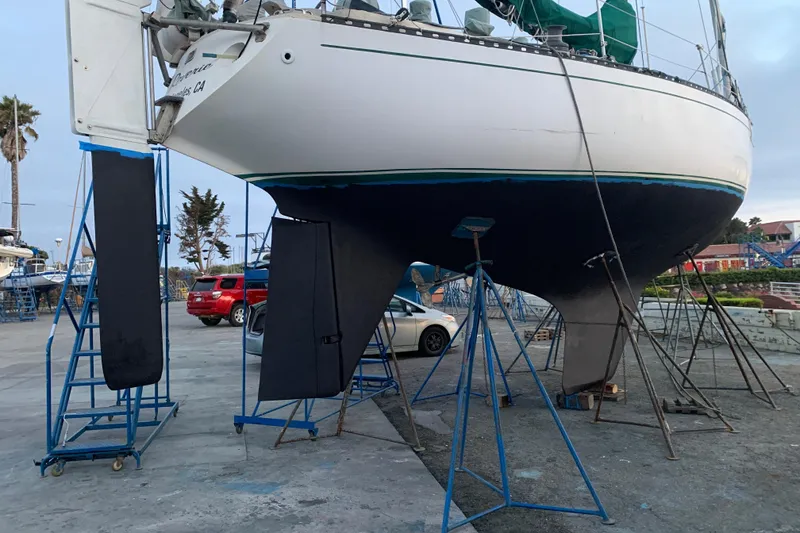 1972 Tartan 41 sailboat on stands in a boatyard, with cars and trees nearby.