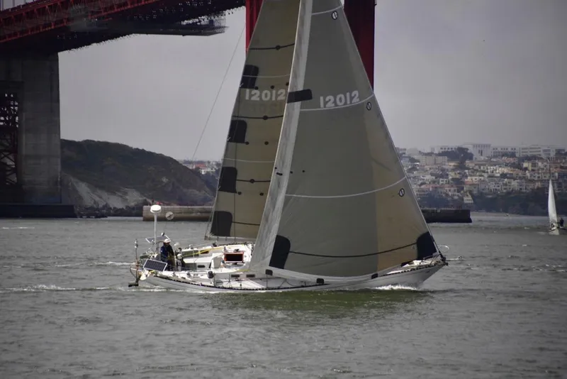 Sailing yacht Tartan 41 (1972) under bridge, cityscape in background.