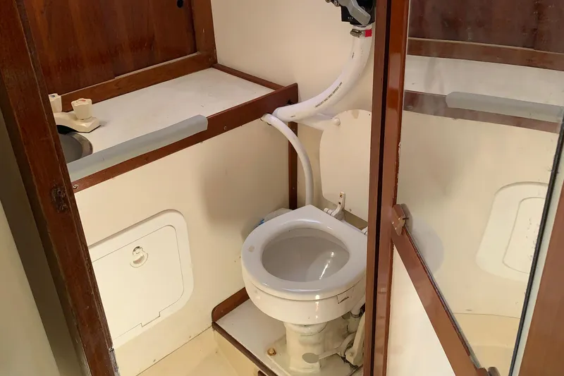 1972 Tartan 41 yacht bathroom with toilet, sink, and wooden cabinetry.
