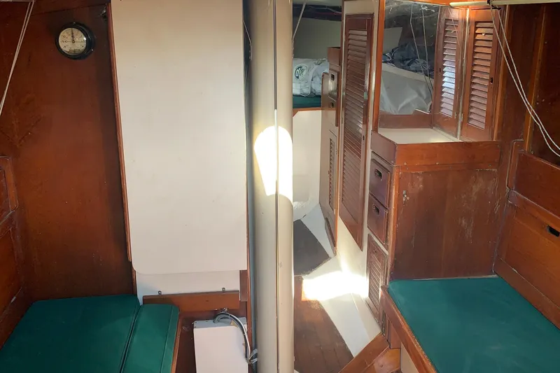 Interior of a 1972 Tartan 41 sailboat with wooden cabinetry and green cushions.