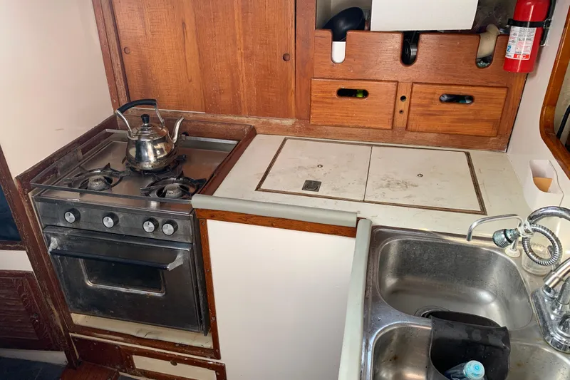 1972 Tartan 41 yacht kitchen with stove, sink, and wooden cabinets.