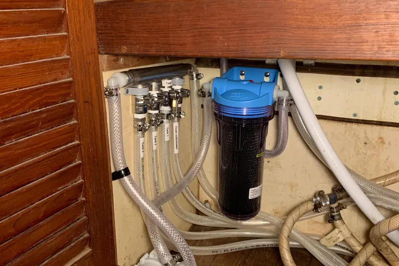 Plumbing system in a 1972 Tartan 41 sailboat with water filter and hoses.