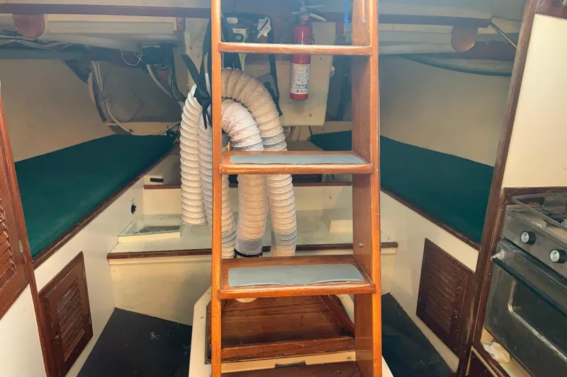 Interior of a 1972 Tartan 41 sailboat with wooden ladder and green cushions.