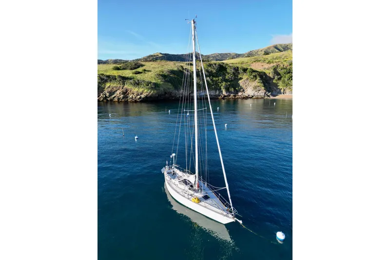 Sailboat Tartan 41 (1972) anchored in scenic bay with lush hills in background.