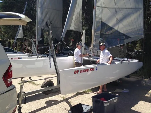 Two people preparing a 1989 Nacra 5.8 sailboat on a sunny day.