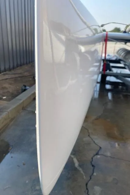 1989 Nacra 5.8 catamaran hull, close-up view, on a wet concrete surface.