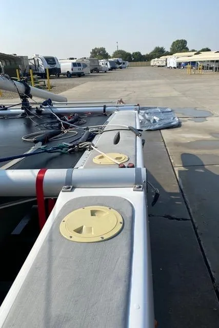 1989 Nacra 5.8 catamaran on a concrete surface, surrounded by parked vehicles.