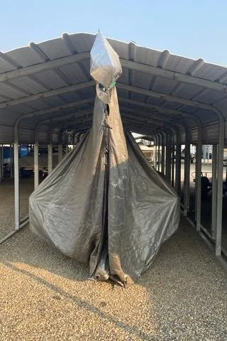 Covered 1989 Nacra 5.8 catamaran stored under a metal shelter.