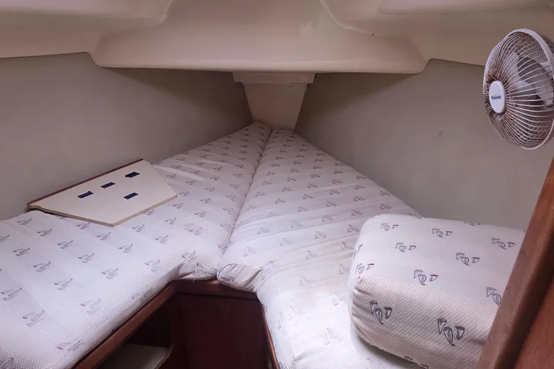 Cozy cabin interior of 1995 Hunter 336 sailboat with patterned bedding and fan.
