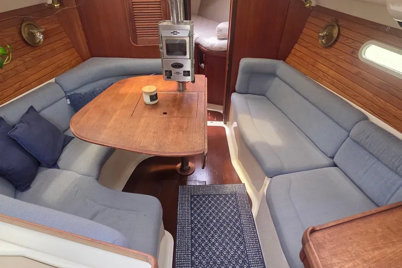 Cozy interior of a 1995 Hunter 336 sailboat with blue seating and wooden table.