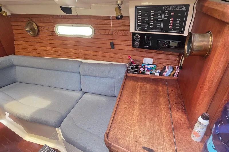 Interior of a 1995 Hunter 336 sailboat with wooden paneling and a cozy seating area.