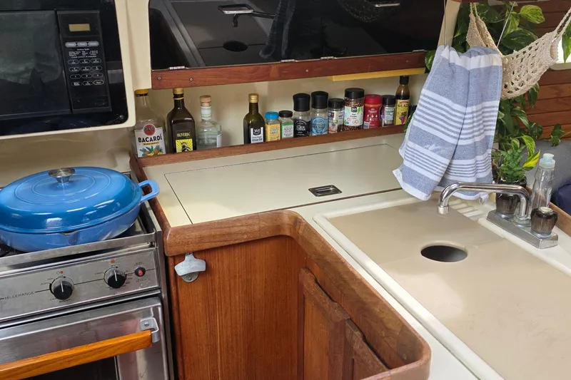 Compact kitchen in a 1995 Hunter 336 sailboat with stove, sink, and spices.
