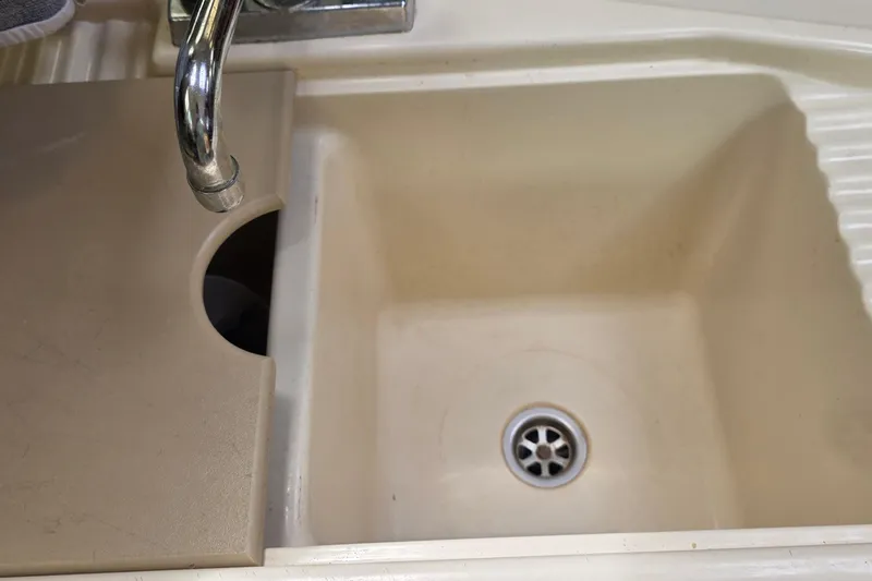 Cream-colored sink with faucet and drain, partially covered, in a 1995 Hunter 336.