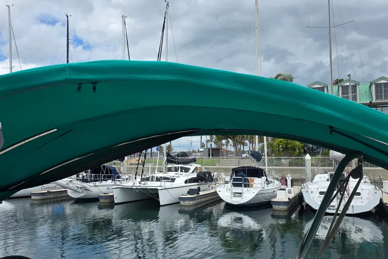 Marina view with Hunter 336 sailboat, 1995 model, under teal canopy on a cloudy day.
