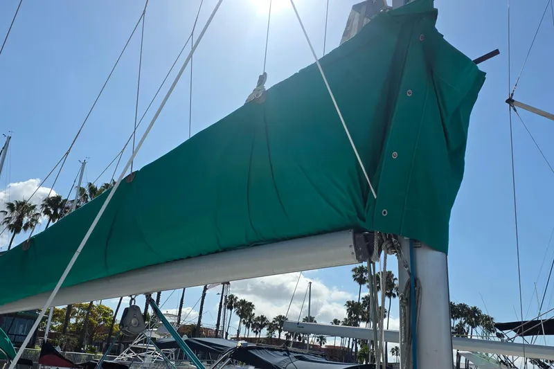Sailboat mast with green sail cover, Hunter 336, 1995 model, under clear blue sky.