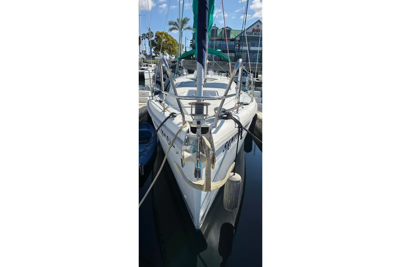 1995 Hunter 336 sailboat docked at marina, clear sky, palm trees in background.