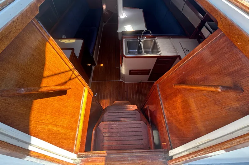 Interior view of 1988 Catalina 34 sailboat, featuring wooden finishes and compact kitchen area.