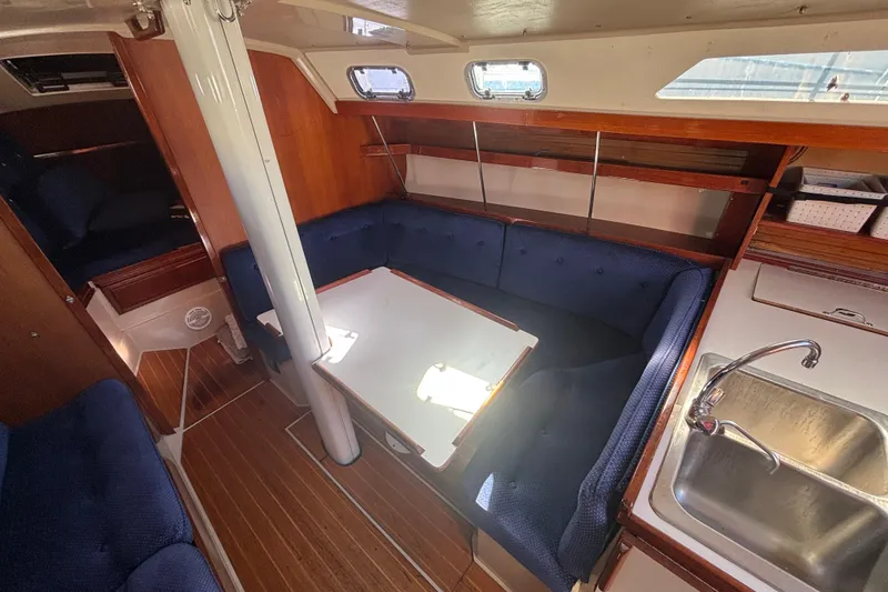 Interior of a 1988 Catalina 34 sailboat with cozy seating and a compact kitchen area.